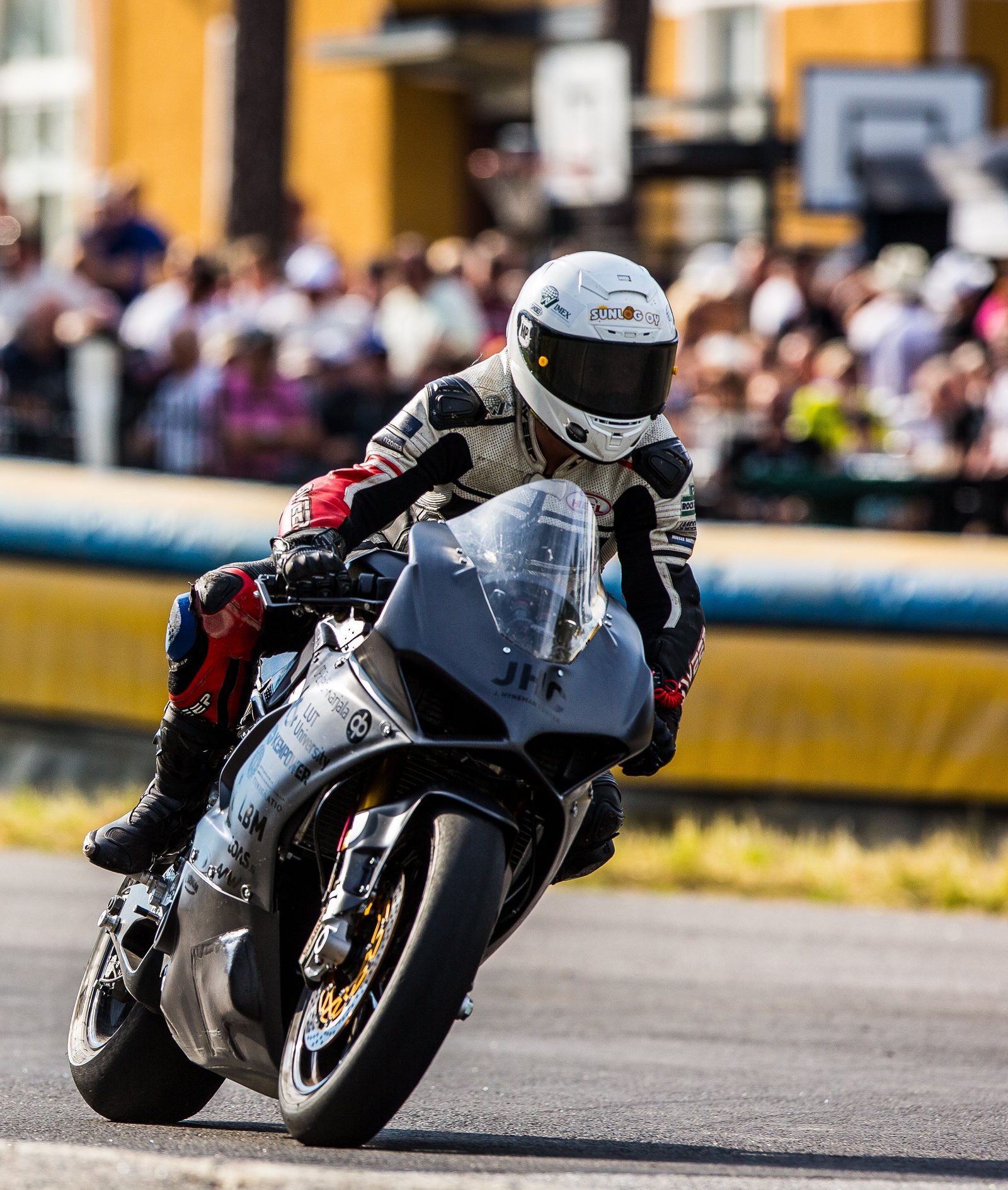 Pauli Pekkanen riding Mk1 on the Imatra street circuit, leaned into a corner with spectators lining the barriers behind him.